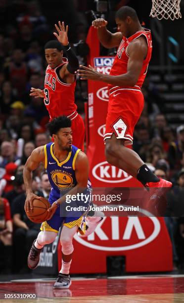 Quinn Cook of the Golden State Warriors looks to pass as Shaquille Harrison and Cristiano Felicio of the Chicago Bulls leap behind him at the United...
