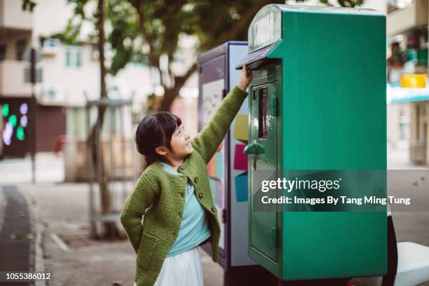 lovely little girl posting a letter joyfully in a green post box - sending bildbanksfoton och bilder