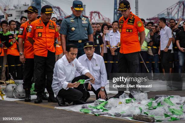Indonesia's President Joko Widodo , holds a personal item from Lion Air flight JT 610 at the Tanjung Priok port on October 30, 2018 in Jakarta,...