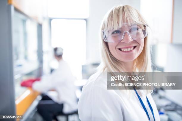 doctor wearing protective goggles and smiling - science photo library photos et images de collection