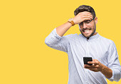 Young handsome man texting using smartphone over isolated background stressed with hand on head, shocked with shame and surprise face, angry and frustrated. Fear and upset for mistake.