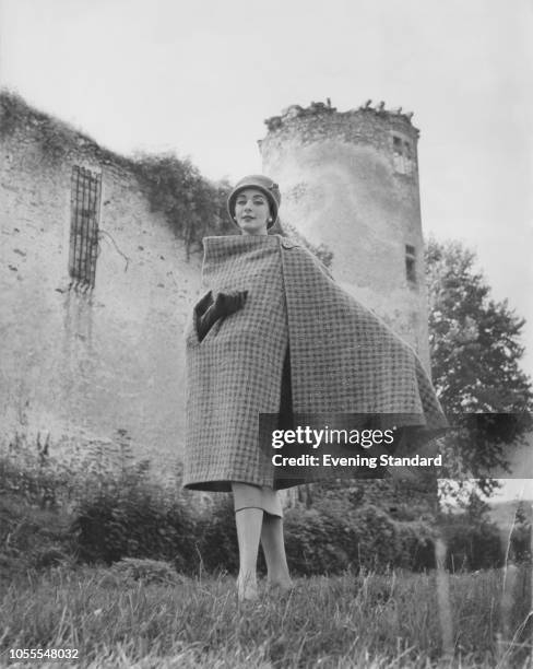 Model wearing a checked tweed cape by French fashion designer Hubert de Givenchy, February 1957. The cape features an armhole for carrying a handbag.