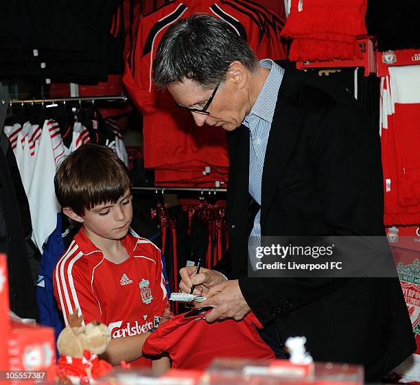 In this handout image supplied by Liverpool Football Club, John W Henry of NESV signs an autograph for a young fan in the Liverpool F.C. Shop at...