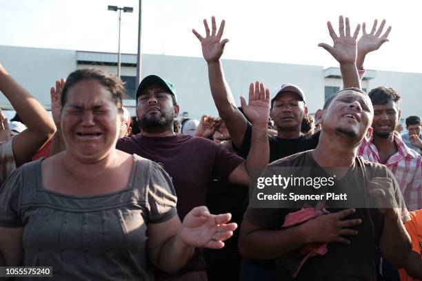 Members of the Central American caravan react while listening to a meeting and spiritual service at an evening camp on October 30, 2018 in Juchitan,...