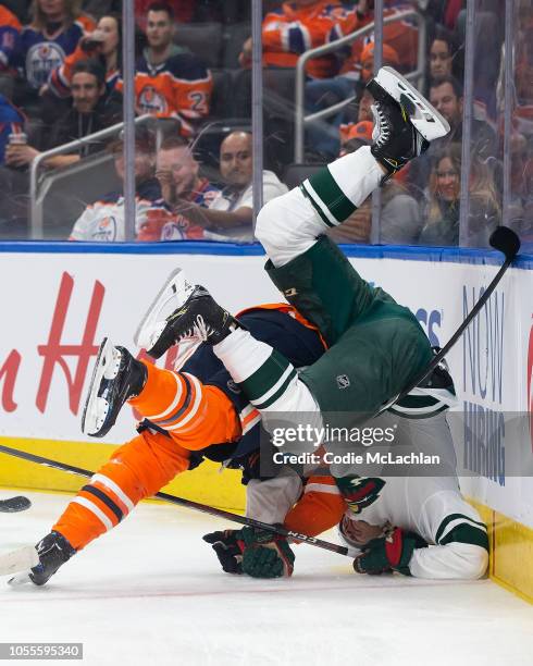 Adam Larsson of the Edmonton Oilers hits Joel Eriksson Ek of the Minnesota Wild at Rogers Place on October 30, 2018 in Edmonton, Alberta, Canada.