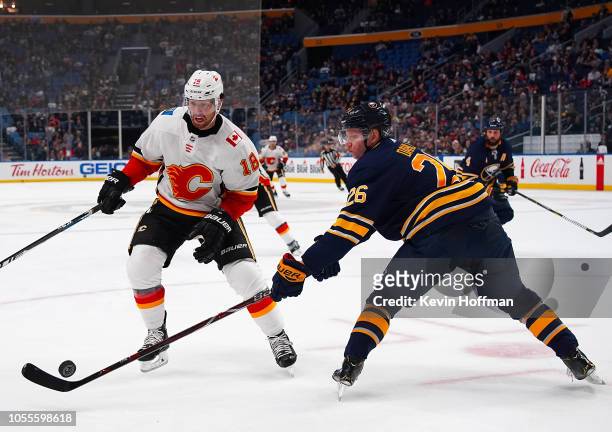 Rasmus Dahlin of the Buffalo Sabres pokes the puck away from James Neal of the Calgary Flames during the third period at the KeyBank Center on...