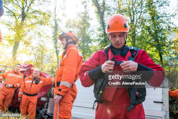 brandweerman in een droog pak voorbereiden op de reddingsoperatie aan de rivier - red suit stockfoto's en -beelden