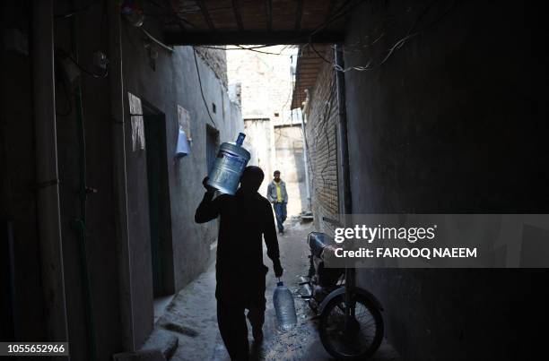 Pakistani man carries water bottles as he walks at a Christian colony in Islamabad on October 31 after the Supreme Court decision to overturn the...