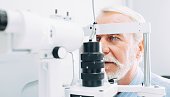 Senior man getting eye exam at clinic, close-up
