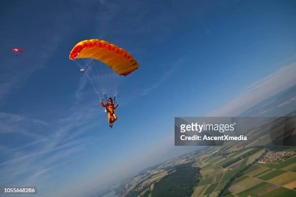 parapente se desliza hacia la tierra - salto en paracaidas fotografías e imágenes de stock