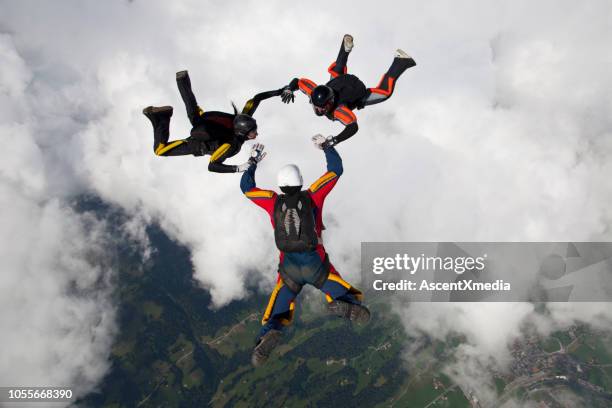 skydivers fall towards the earth - three people stock pictures, royalty-free photos & images