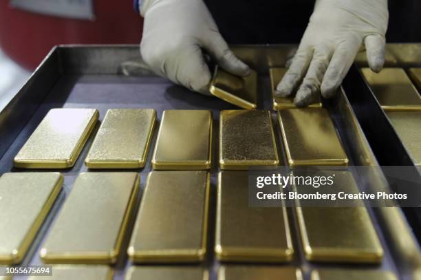 an employee arranges one kilogram gold bars - barren stock-fotos und bilder