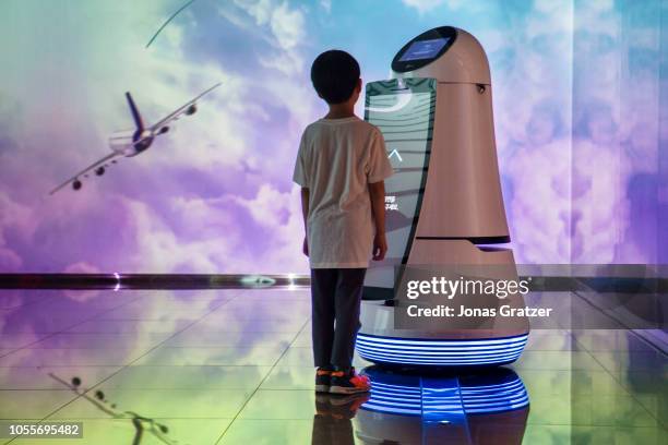 Young boy communicating with a robot that is on display at Incheon International Airport in Seoul / South Korea. The Guide Robot recognises...