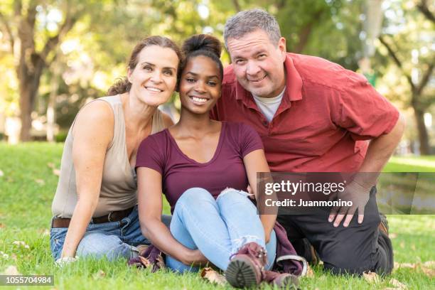 mature caucasian couple posing with their black adopted daughter - adoption stock pictures, royalty-free photos & images