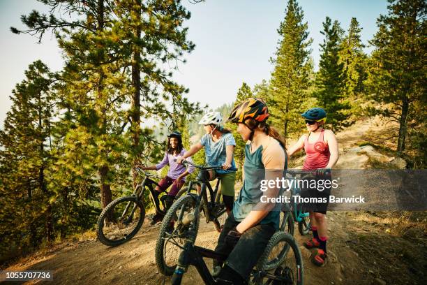 group of female mountain bike riders resting during ride on summer evening - andare in mountain bike foto e immagini stock