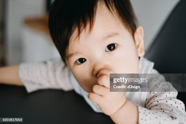 cute baby girl sitting on high chair sucking her thumb - thumb sucking stock pictures, royalty-free photos & images