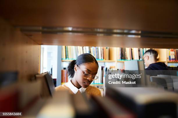 male and female students reading books in university library - choice student stockfoto's en -beelden