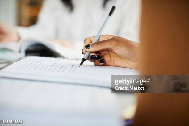 cropped hand of woman writing on book while studying at table - holding pen in hand stock pictures, royalty-free photos & images