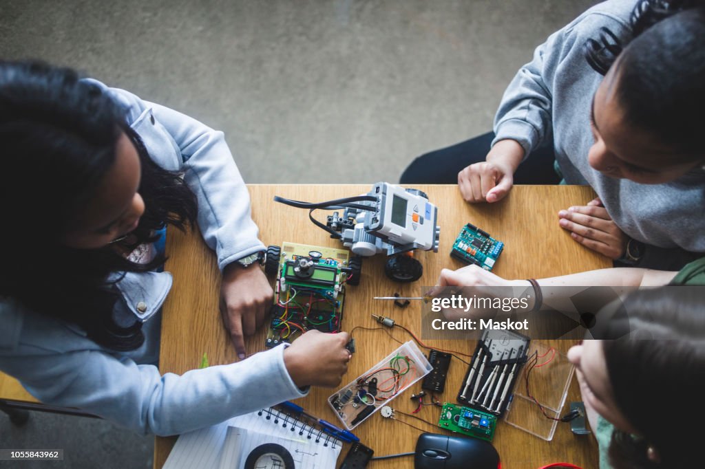 High angle view of multi-ethnic female students preparing science project at desk in high school classroom