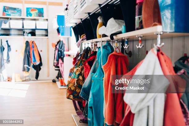 various clothes hanging from hooks in cloakroom at preschool - coat check stock pictures, royalty-free photos & images