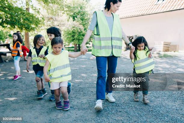 teacher walking with students in playground at kindergarten - child care stock pictures, royalty-free photos & images