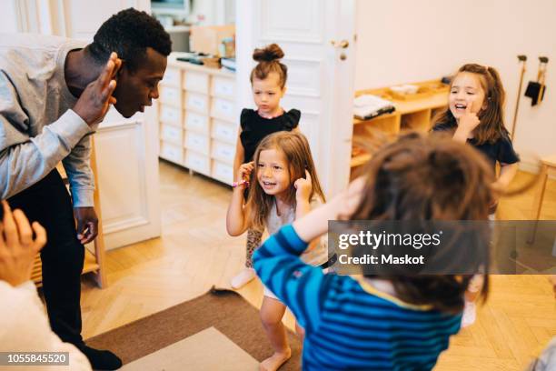 high angle view of teachers and students dancing in classroom at child care - dance instructor stock-fotos und bilder