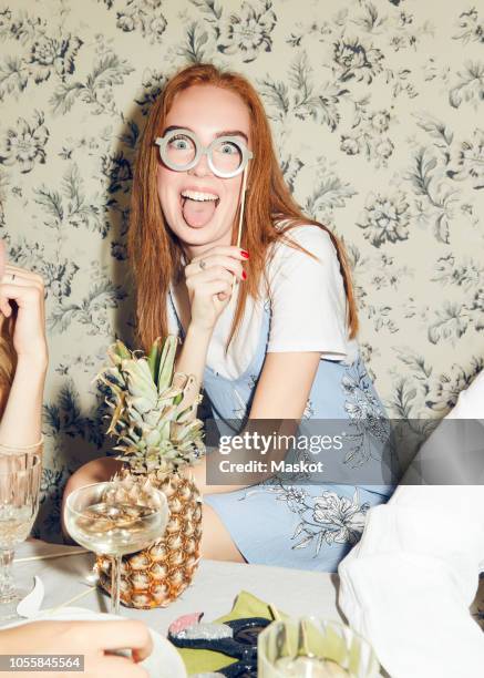 portrait of young redhead woman holding prop while sitting amidst friends during dinner party at home - 小道具 ストックフォトと画像