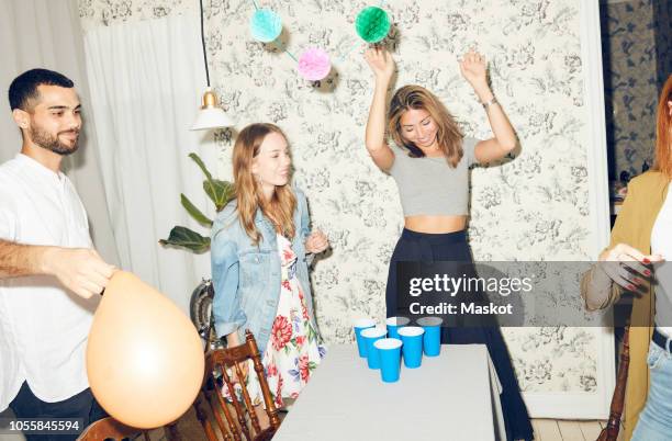 young multi-ethnic friends enjoying beer pong game at apartment during dinner party - beirut stockfoto's en -beelden