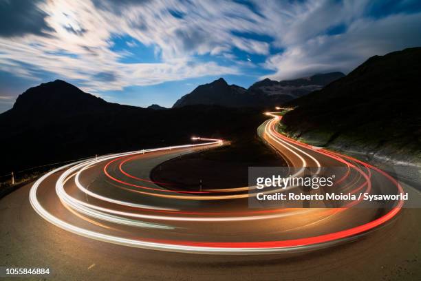 car lights, bernina pass, switzerland - licht stock-fotos und bilder