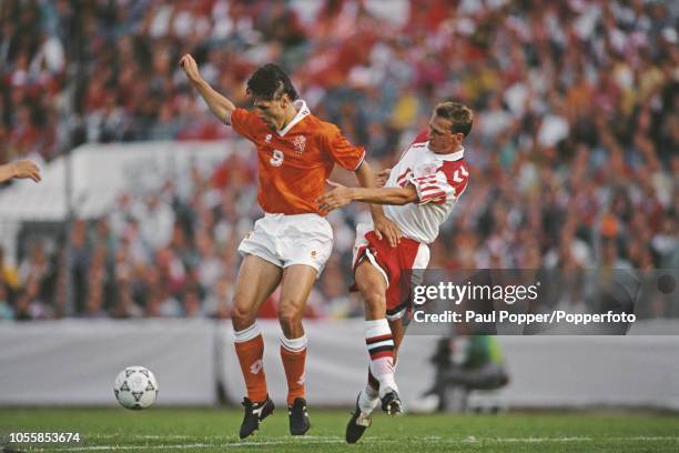 Dutch professional footballer Marco van Basten shields the ball from Danish player Torben Piechnik during play in the semi-final match between...