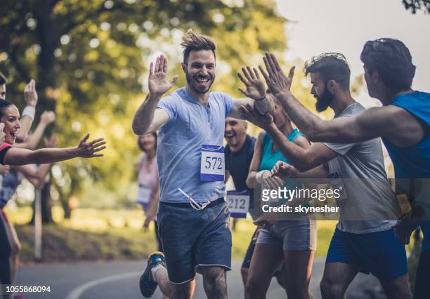 glücklich marathon läufer gruß gruppe von athleten auf ziellinie. - marathon stock-fotos und bilder
