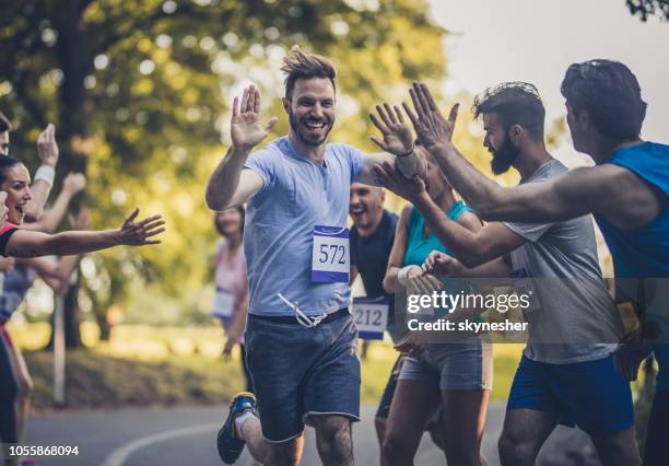 gelukkig marathon loper groet groep van atleten op de finishlijn. - finale wedstrijd stockfoto's en -beelden