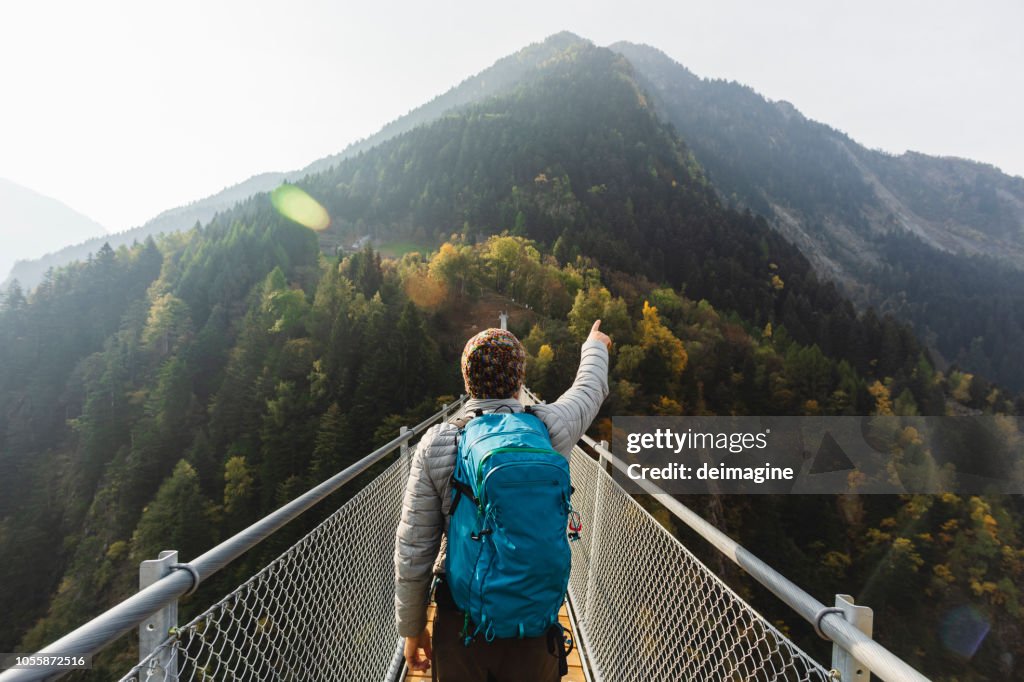 Caminante solitario señalando con la mano en el puente de la suspensión