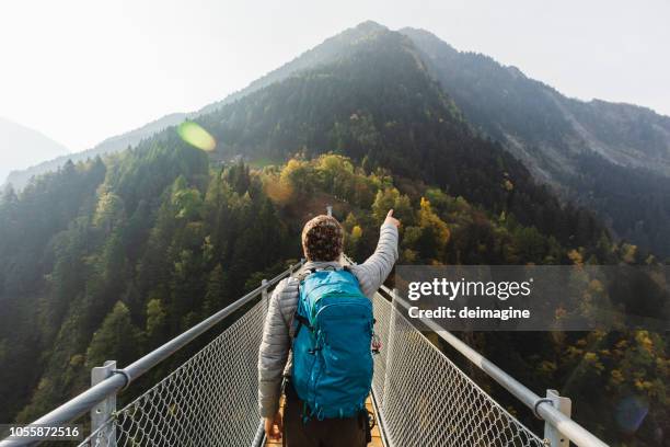 caminante solitario señalando con la mano en el puente de la suspensión - soñar un futuro fotografías e imágenes de stock