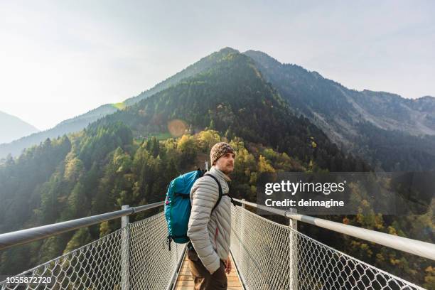 solo hiker looking at view on suspension bridge - bridge side view stock pictures, royalty-free photos & images