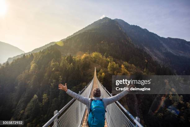 solo wandelaar met open armen op hangbrug - hangbrug stockfoto's en -beelden