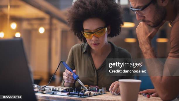 young woman soldering a circuit boards in her tech office - soldered stock pictures, royalty-free photos & images