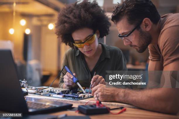 young woman soldering a circuit boards in her tech office - repairing electronics stock pictures, royalty-free photos & images