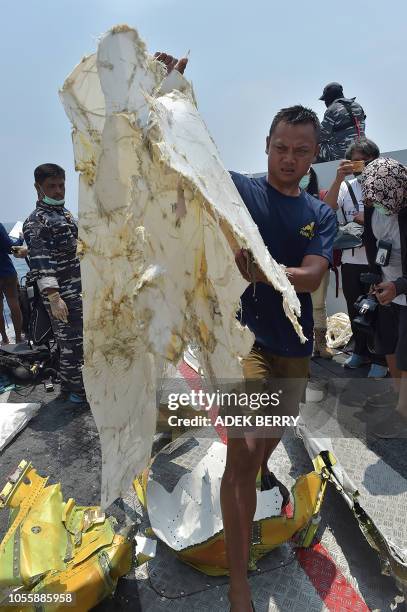 Member of the Indonesian Navy carries part of the ill-fated Lion Air flight JT 610 onto the deck of their ship during search operations at sea, north...