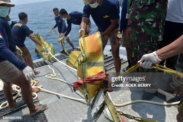 Members of the Indonesian Navy place parts of the ill-fated Lion Air flight JT 610 onto the deck of their ship during search operations at sea, north...