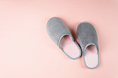Gray and pink home slippers on a pastel paper background. Top view. Copy space