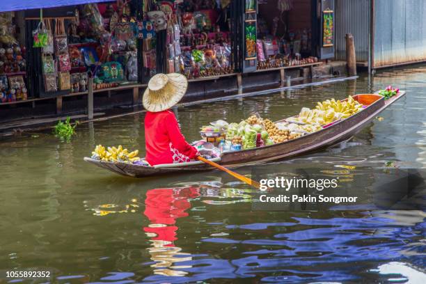 asian senior female selling many thai fruit at damnoen saduak floating market in ratchaburi near bangkok - thai canal photos et images de collection