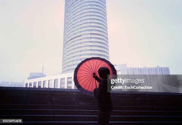 women with red umbrella in front of city skyline - chinese architecture stockfoto's en -beelden