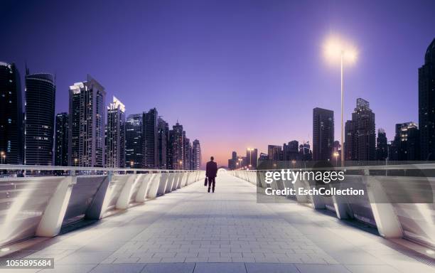 businessman at pedestrian overpass in modern city at sunset - dubai people stock pictures, royalty-free photos & images