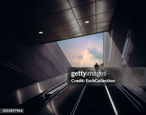 Businessman on escalator moving towards sky with rainbow Businessman on escalator moving towards sky with rainbow