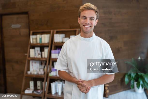 homem feliz trabalhando num spa, vendendo produtos de beleza - terapeuta de beleza - fotografias e filmes do acervo