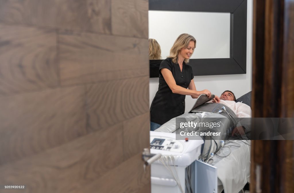 Beautician working at a spa doing a pressotherapy session to a woman