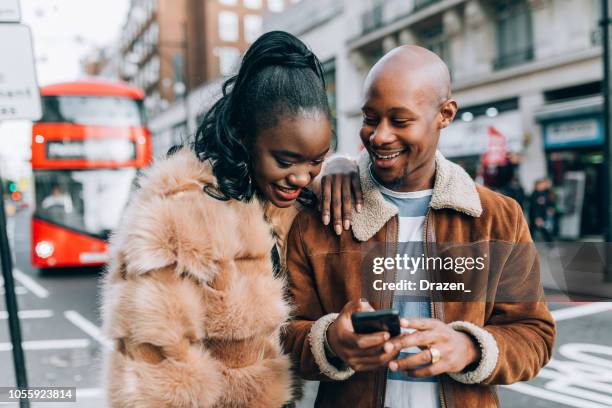 tourists using phone and wi-fi in downtown - street style couple stock pictures, royalty-free photos & images
