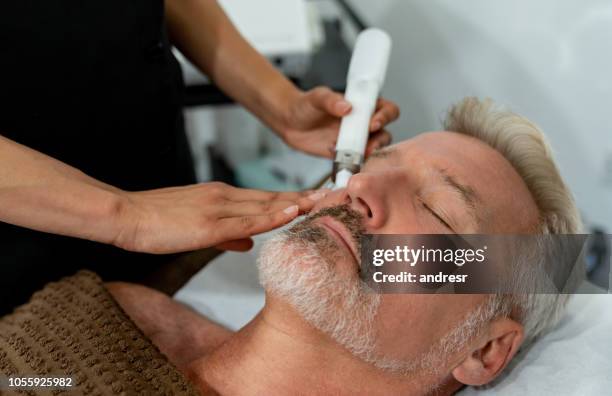 handsome man at the spa getting a facial - laser face stock pictures, royalty-free photos & images
