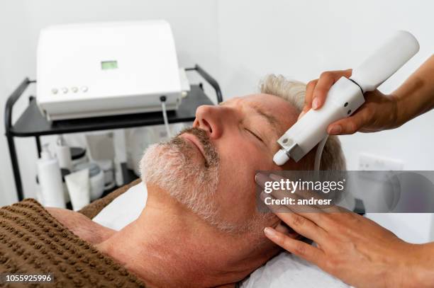 man at the spa getting a facial laser treatment - laser stock pictures, royalty-free photos & images